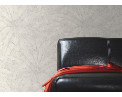 Wanddecoratie met bladmotief naast een zwarte leren fauteuil