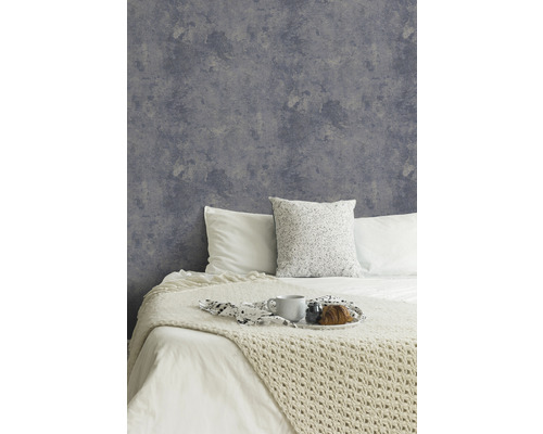 Slaapkamer met grijs vliesbehang in betonlook en gedecoreerd bed