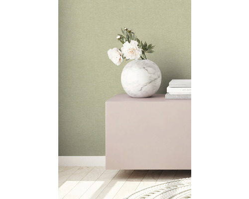 Close-up van een groen gestructureerd behang met een marmeren vaas en boeken op een kast