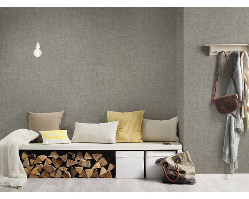 Woonkamer met grijs textielbehang, zitbank met kussens, houtblokken en opbergboxen