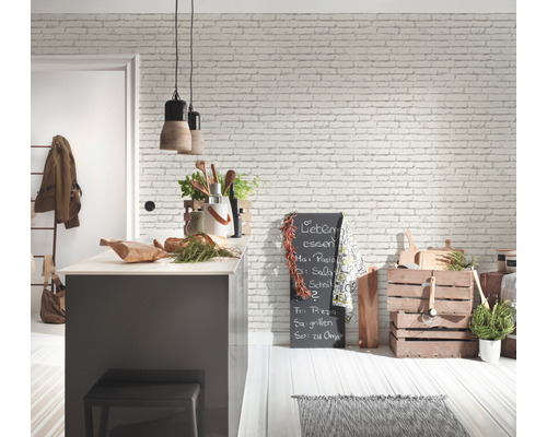 Lichte keukenruimte met kookeiland, schoolbord en houten accenten tegen een witte bakstenen muur