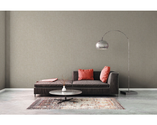 Woonkamer met beige vliesbehang, bank, tafel en vloerlamp