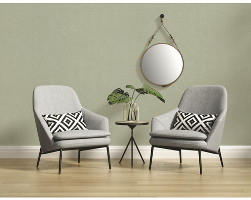 Licht interieur met twee grijze fauteuils, een bijzettafel en een ronde spiegel aan de muur