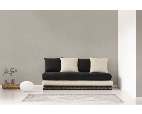 Lichte kamer met een bank, meerdere kussens, een kleine tafel, een lamp en een vloerkleed.