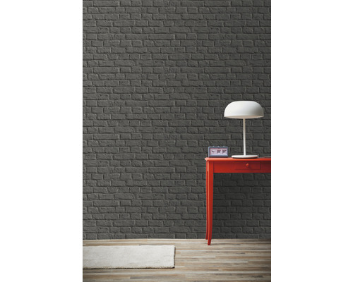 Kamer met grijze bakstenen muur, rode tafel en lamp.