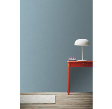 Scene met rode tafel, witte lamp en klok tegen een muur