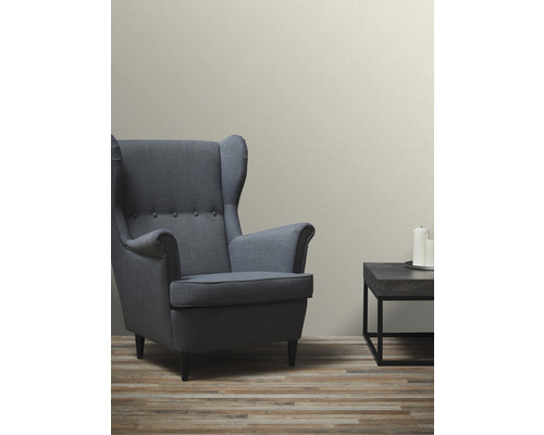 Woonkamer met fauteuil, tafel en patroonbehang voor een gezellige sfeer.