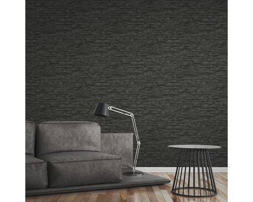 Woonkamer met bank, staande lamp, bijzettafel en behang met steeneffect.