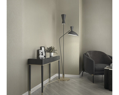 Interieurweergave met console, staande lamp en fauteuil voor een behangen muur.