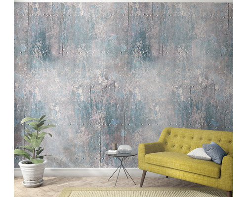 Woonkamer met industrieel behang, bank en plant in pot.