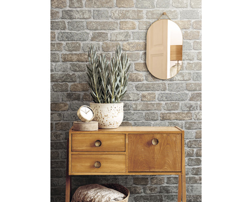 Decoratief interieur met baksteen behangmotief, houten dressoir, spiegel en kamerplant.