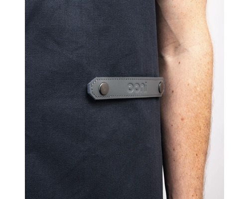 Detail van een barbecueschort met grijs lederen detail en Ooni logo.