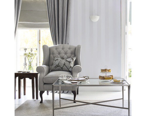 Woonkamer met fauteuil, salontafel, gordijnen en decoratie