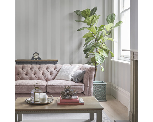 Woonkamer met gestreept behang, bank, tafel en kamerplant.