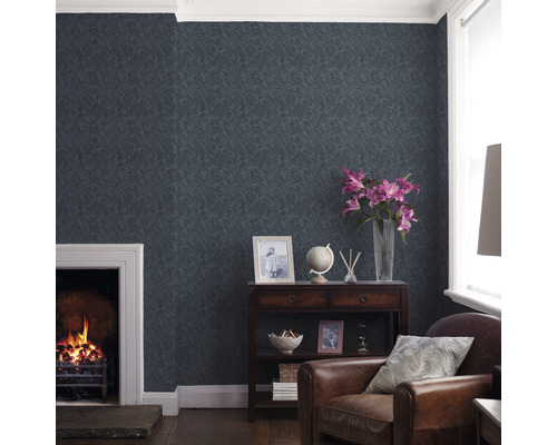 Woonkamer met patroonbehang, open haard en bruine lederen fauteuil