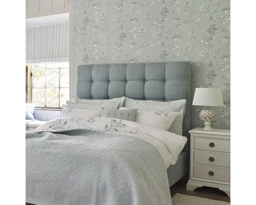 Slaapkamer met bed, nachtkastje en bloemenbehang voor een heldere en vriendelijke sfeer