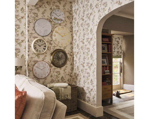 Woonkamer met bloemenbehang en een verzameling wandklokken in verschillende ontwerpen