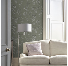 Woonkamer met bank, vloerlamp en behang met bloemmotief