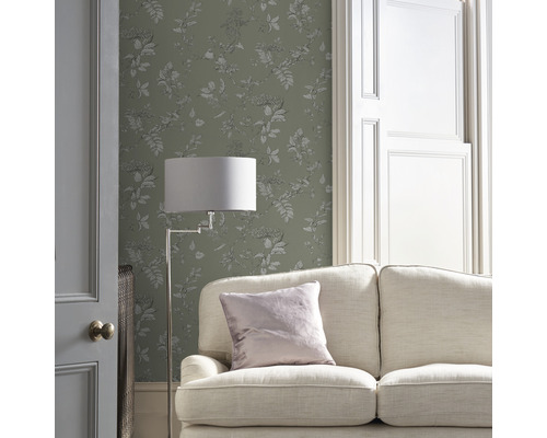 Woonkamer met bank, vloerlamp en behang met bloemmotief