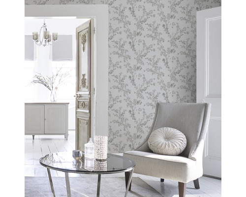 Lichte woonkamer met behang met bloemenmotief, fauteuil, tafel en decoratie