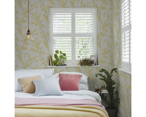 Slaapkamer met bed, kussens, luiken en bloemenbehang