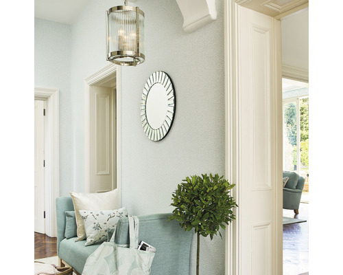 Entree met een bank, een ronde spiegel, een hanglamp en een kamerplant