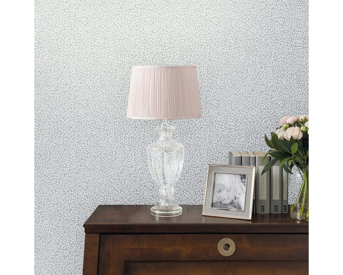 Decoratief behang met bladerpatroon, gecombineerd met een lamp, fotolijst, boeken en een boeket bloemen op een tafel