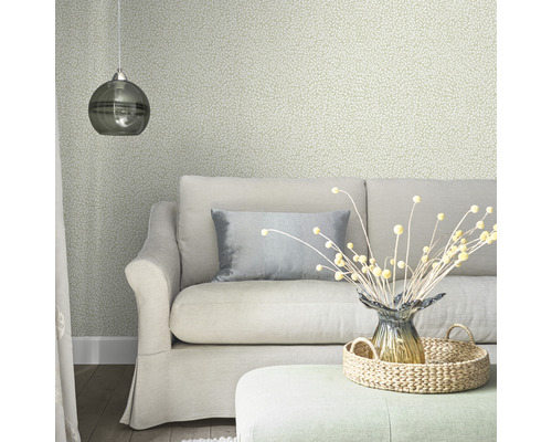 Woonkamer met bank, kussen, lamp, decoratie en behang met motief.