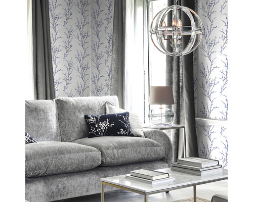 Woonkamer met grijze bank, salontafel, lamp en behang met bloemmotief