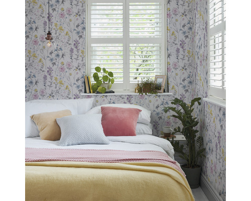 Slaapkamer met bloemenbehang, bed, kussens en raam met luiken