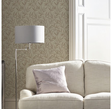 Woonkamer met bank, staande lamp en behang met bladerpatroon