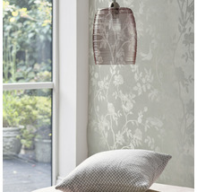 Hanglamp en behang met bloemmotief in een heldere kamer.