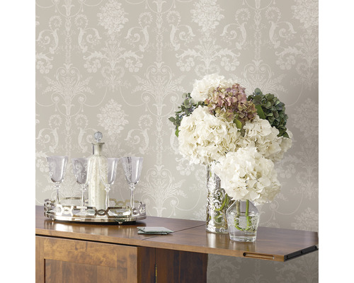 Behang met bloemmotief boven een houten kast met bloemstukken en drankaccessoires