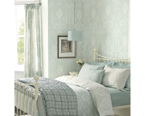 Lichte slaapkamer met bed, behang met patroon, gordijnen en lamp