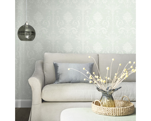 Woonkamer met patroonbehang, bank, kussen, tafeldecoratie en hanglamp