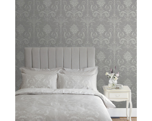 Slaapkamer met bed, nachtkastje en behang met damastpatroon