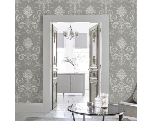 Woonkamer met grijs patroonbehang, zicht door een deur naar een andere kamer