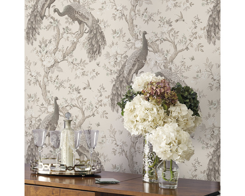 Interieur met patroonbehang met pauwen, bloemen, drankset op een tafel en bloemen in vazen.