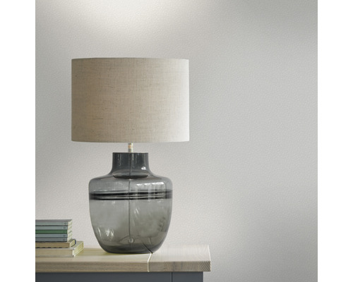 Tafellamp met stoffen kap en glazen voet op een tafel