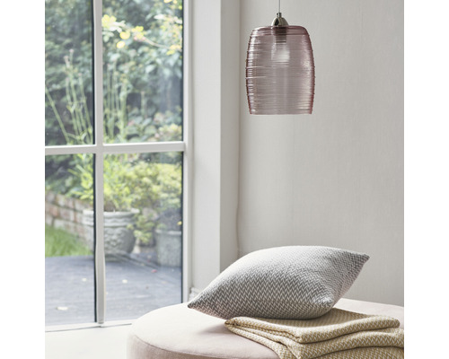 Scene met glazen hanglamp, kussen en deken op een kruk bij een raam