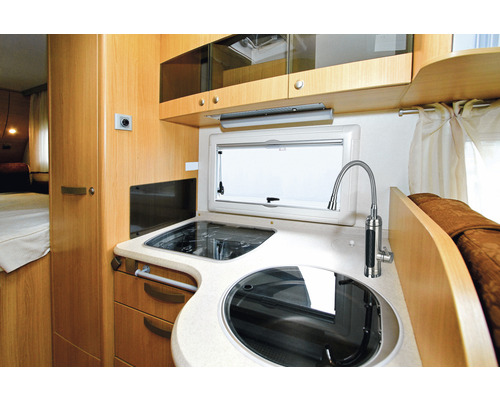 Keukenhoek in een camper met spoelbak, fornuis en keukenraam