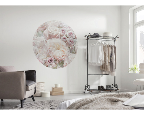 Woonkamer met ronde wanddecoratie met bloemenmotief, kledingrek en fauteuil