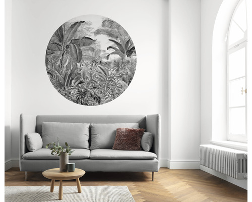 Woonkamer met grijze bank, houten tafel, tapijt en muursticker met jungle thema