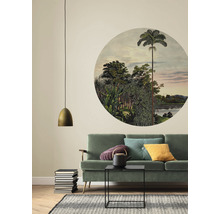 Woonkamer met groene bank, ronde muurschildering met jungle-motief en gouden hanglamp