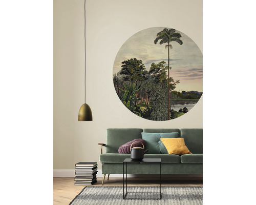 Woonkamer met groene bank, ronde muurschildering met jungle-motief en gouden hanglamp