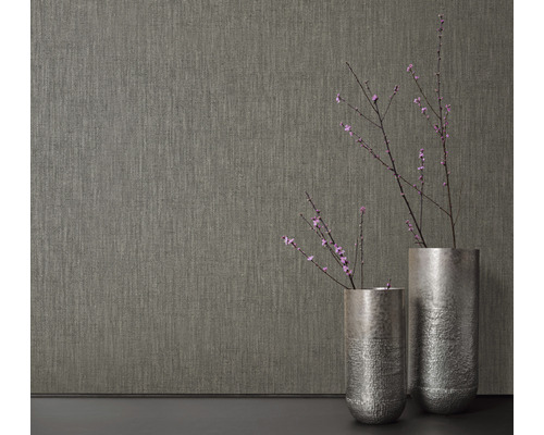 Close-up van een gestructureerd behang naast twee vazen met bloeiende takken.