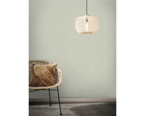 Kamerweergave met rotan stoel, decoratief kussen en rotan lamp voor een gestructureerd wandbehang.