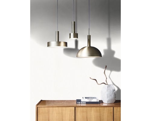 Drie metalen hanglampen hangen boven een houten kast.