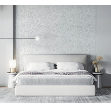 Slaapkamer met bed, nachtkastjes, lampen en bloemenbehang voor een lichte en ruime sfeer.