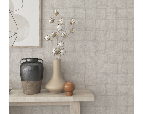 Close-up van verschillende vazen en decoratieve elementen op een houten tafel voor een muur met patroon.